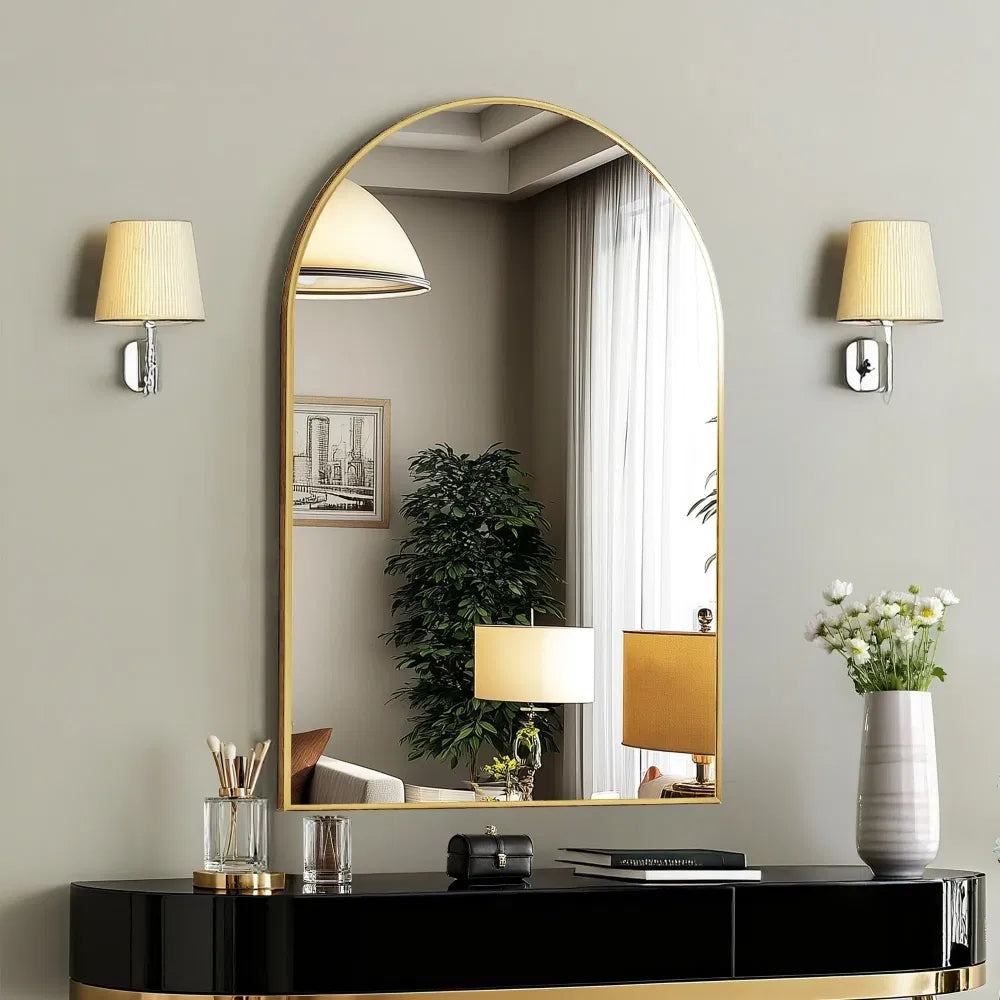Celine arched gold wall mirror above a black console between two wall sconces