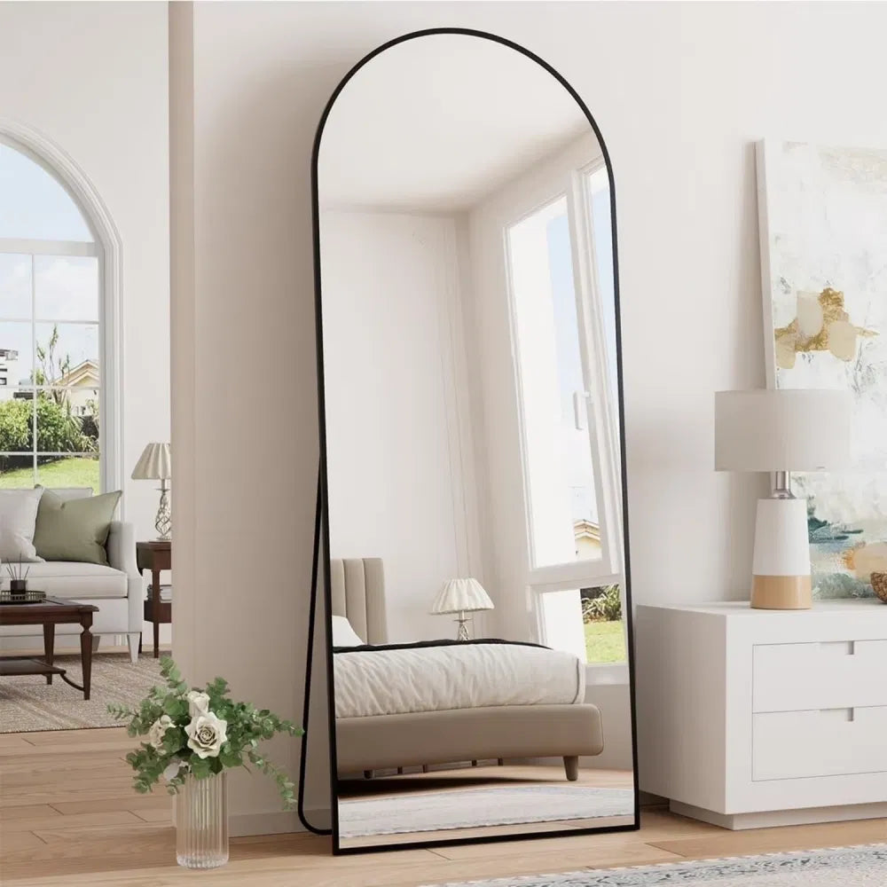 Soleil arched floor mirror in black, 64 x 21 in, leaning in a bright neutral bedroom